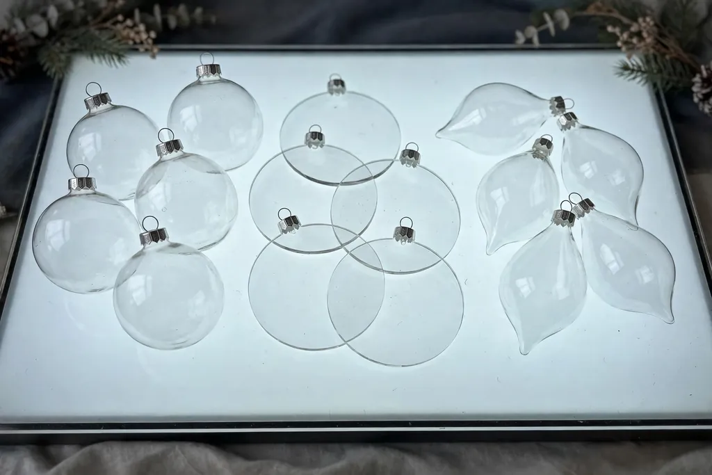 Round, flat disc, and teardrop clear ornaments arranged on a table.