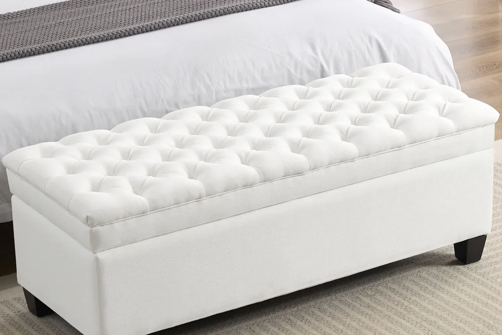 Storage bench at the foot of a bed with a folded throw on top.
