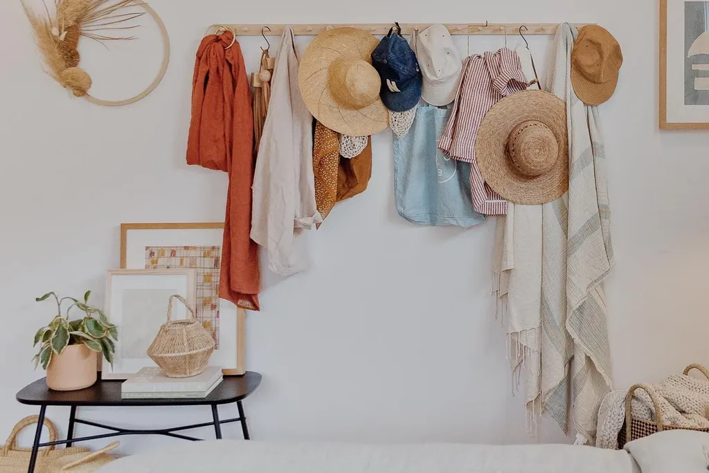 Wooden peg rail on a bedroom wall holding hats, scarves and a bag.