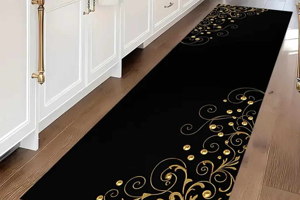 Black kitchen runner rug with a gold scroll pattern in front of white cabinets.