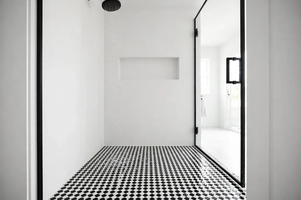Black and white hexagon mosaic tiles on a shower floor behind a glass door.