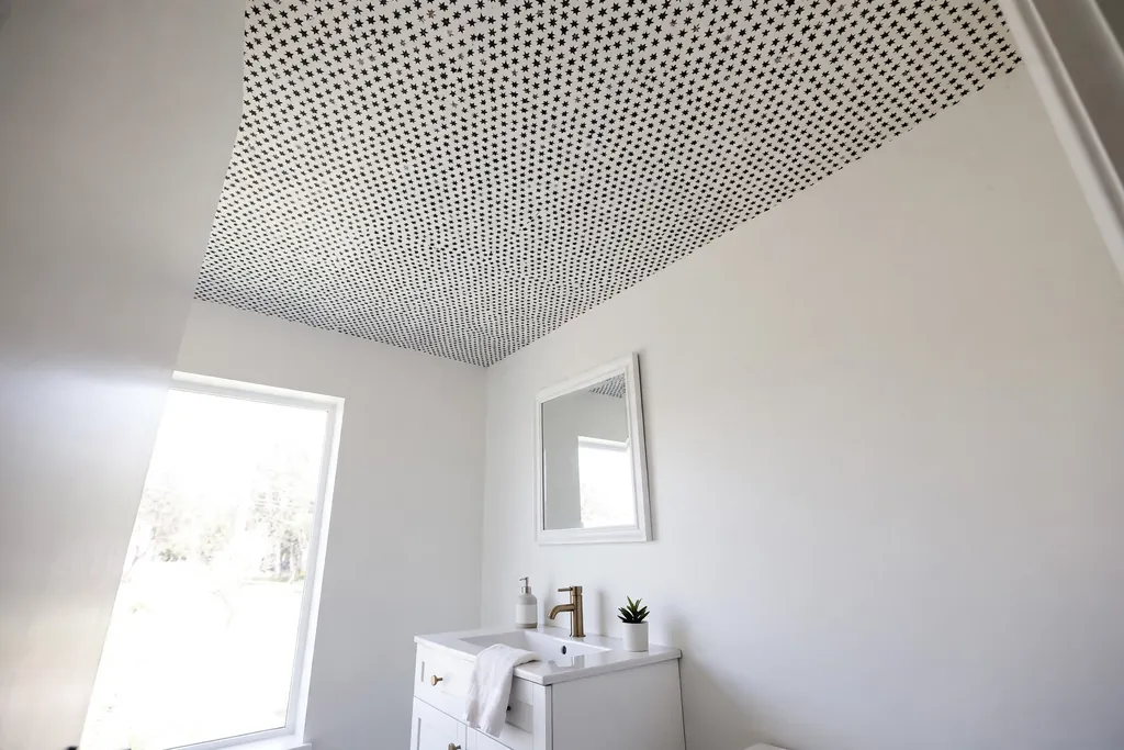 Small bathroom with a small black and white star pattern wallpaper ceiling, plain white walls, and white vanity.