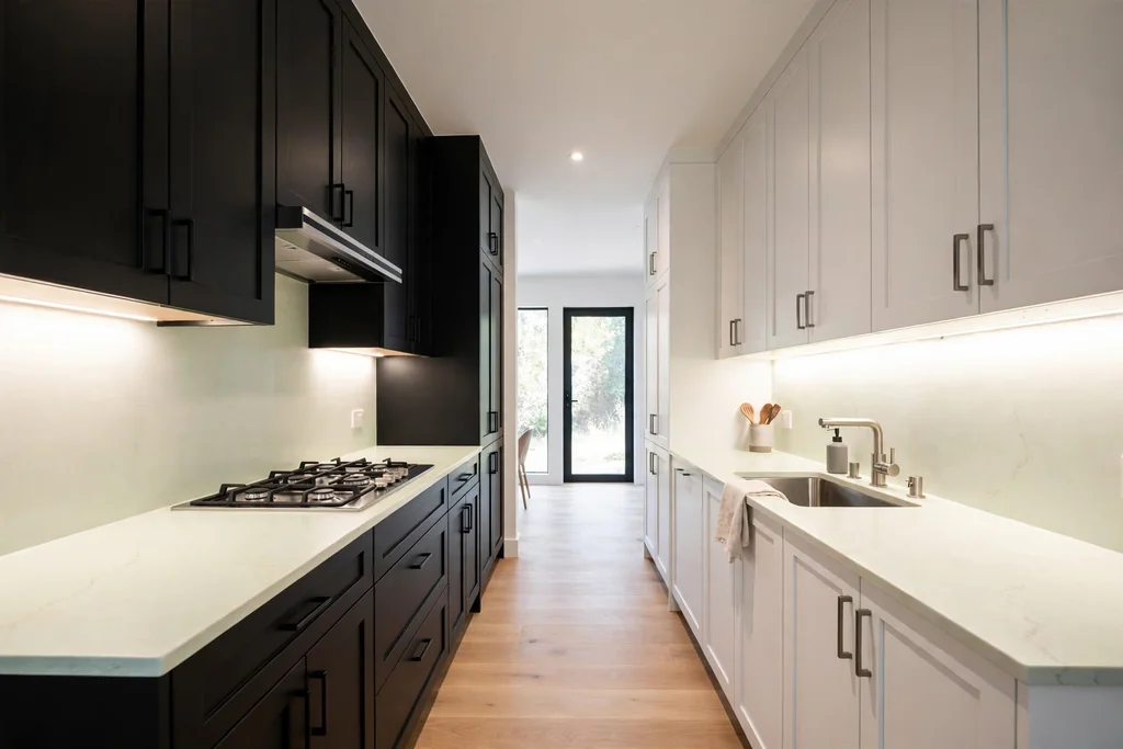 Galley kitchen with black cabinets on one side and white cabinets on the opposite side.