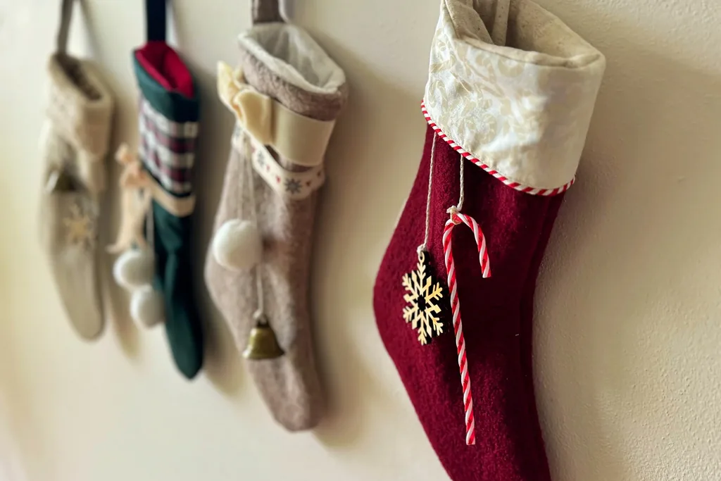 Christmas stockings in red, cream, and green hanging from wall hooks.