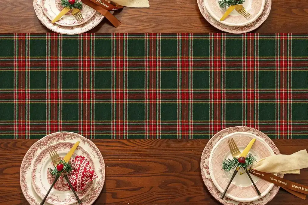 Green and red plaid runner on a wooden table with place settings.