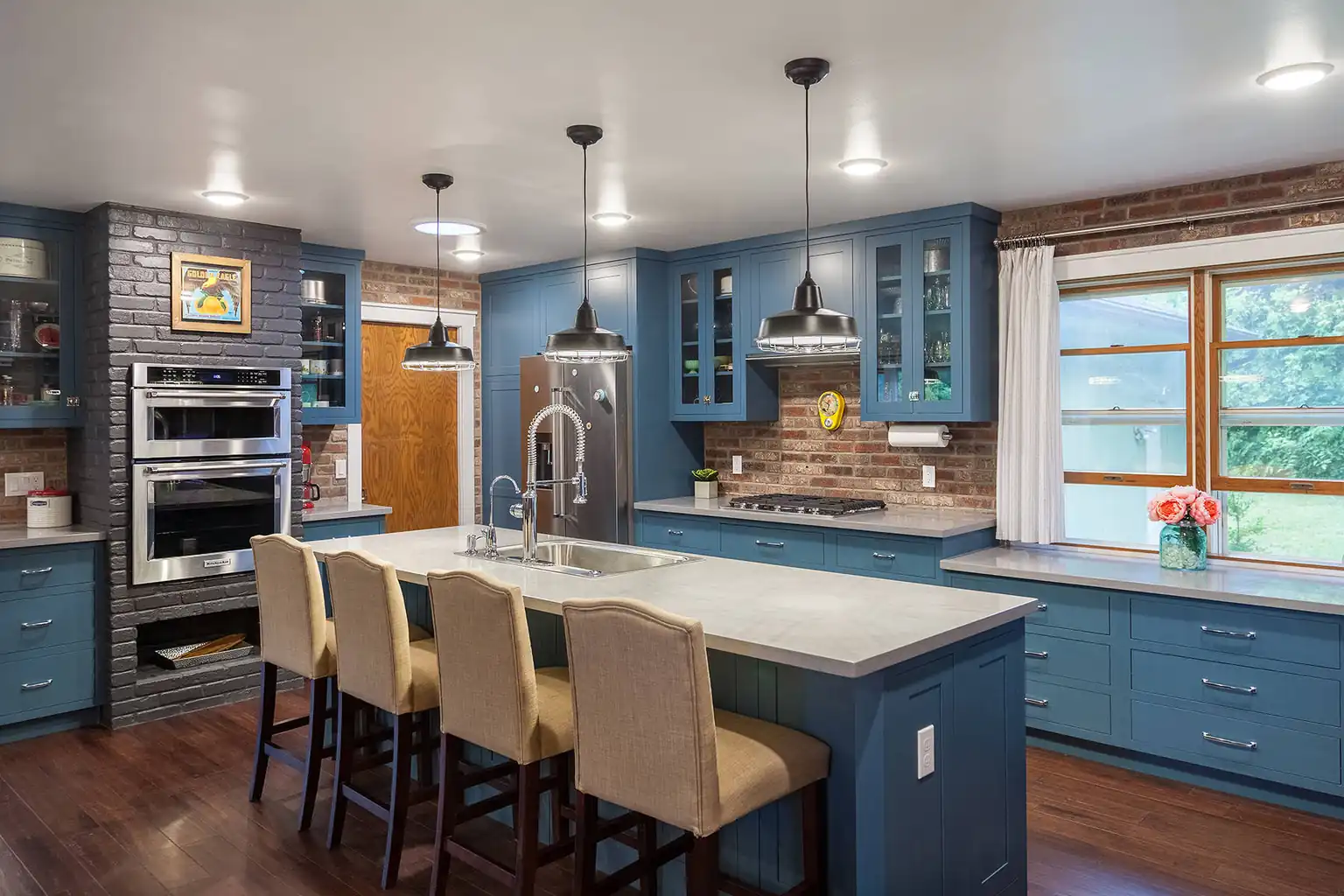 Kitchen with blue painted cabinets, a large island, and stools at the counter.