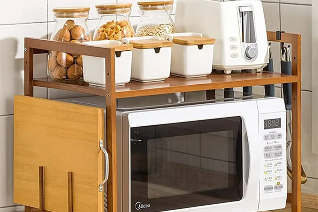 Microwave resting on a cabinet shelf unit with storage below.