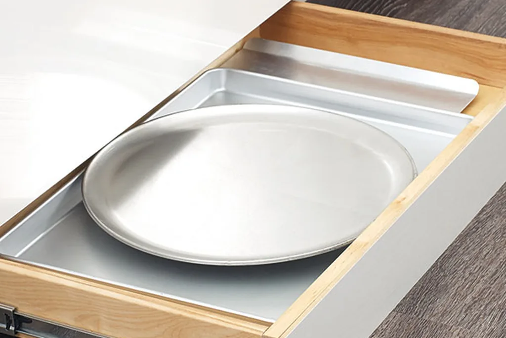 Shallow toe kick drawer open below kitchen base cabinets.