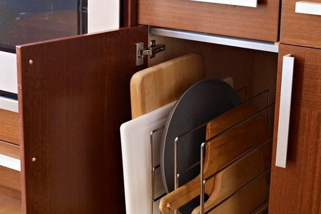 Cutting boards and trays stored upright in vertical dividers inside a cabinet.