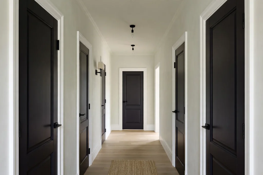 Pale hallway with doors painted deep charcoal and white trim.