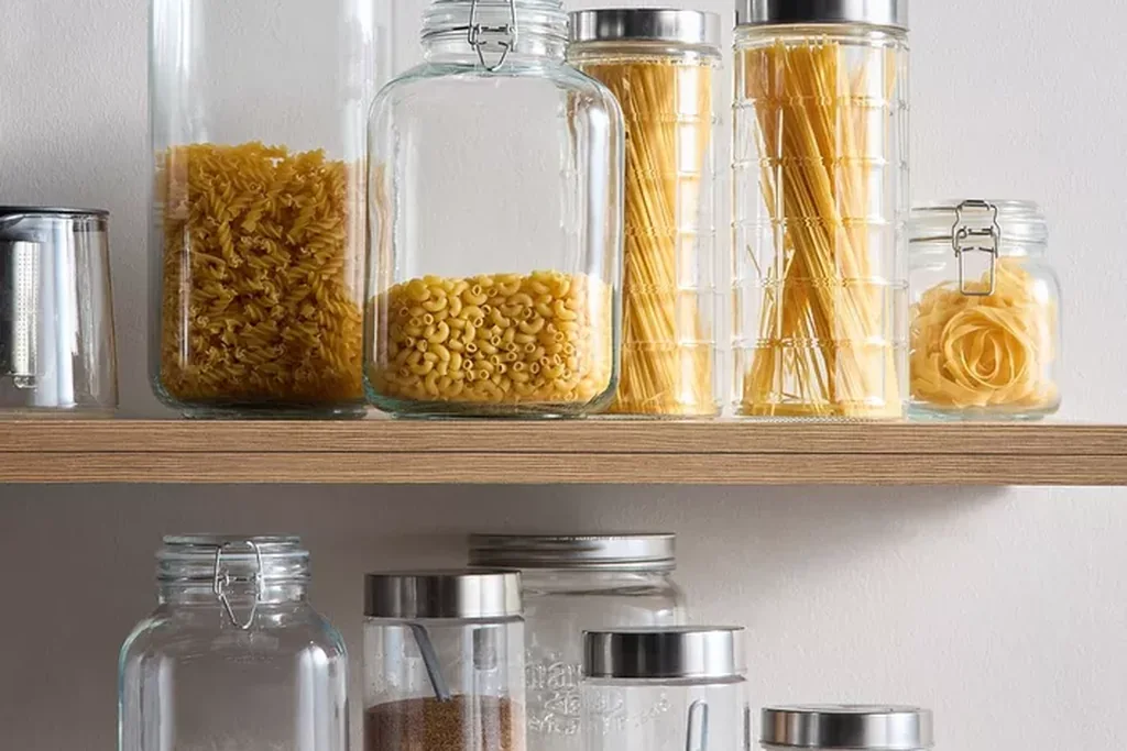 Clear glass jars filled with dry goods lined up on a kitchen counter.