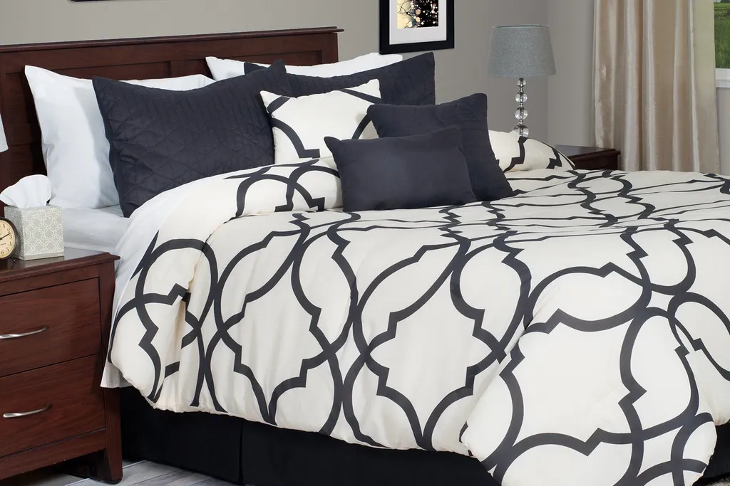 Bed with black and cream bedding and a wood headboard.