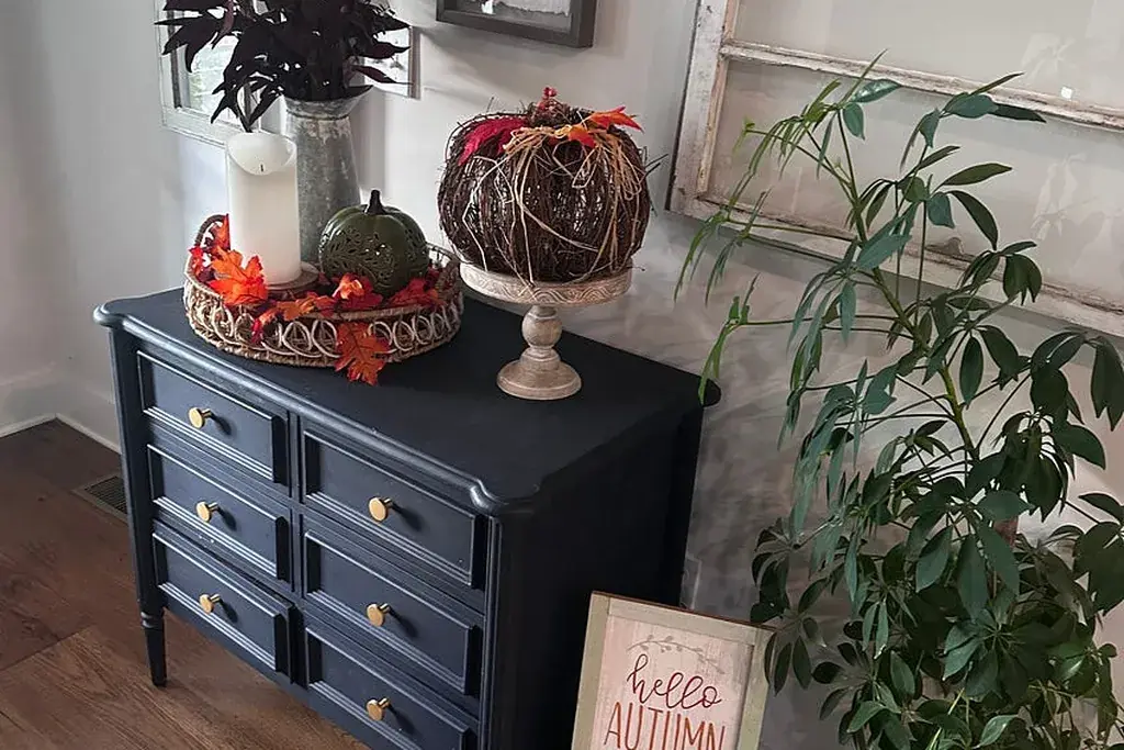 Tray with a pumpkin and framed print on a dresser.