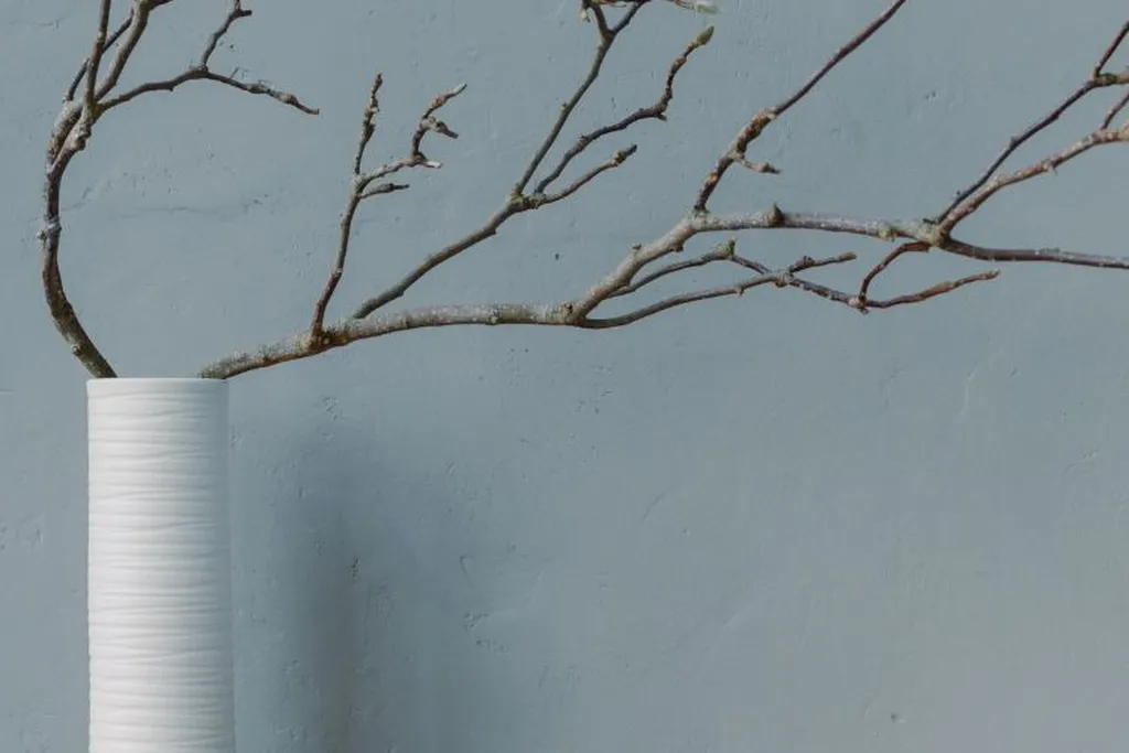 Bare branches in a heavy vase on a dresser.