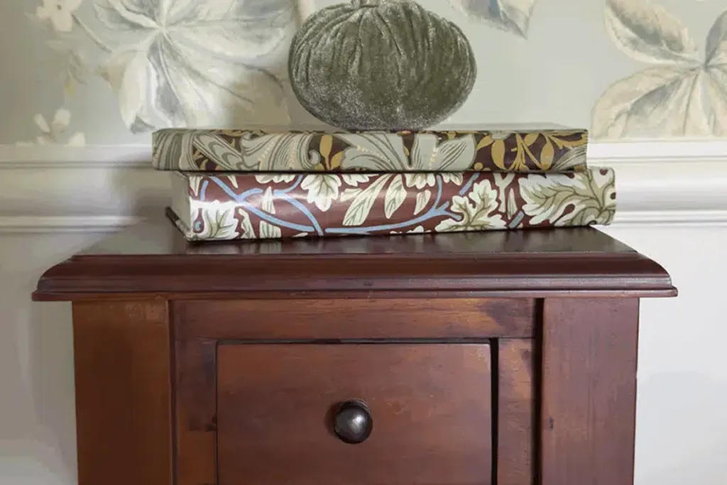 Fabric pumpkins and books on a wood nightstand.