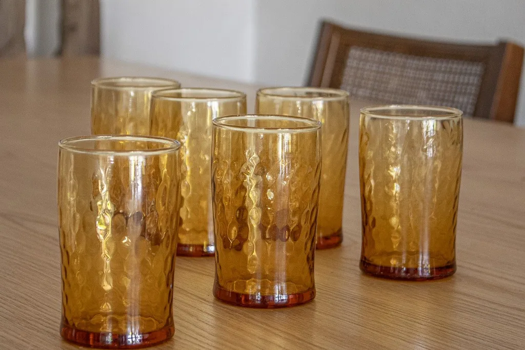Amber drinking glasses standing on a wooden table.