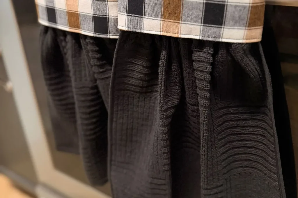 Black dish towels with plaid tops hanging on an oven handle.