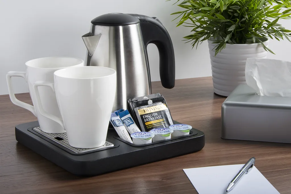 Electric kettle and white mugs arranged on a tray for hot drinks.