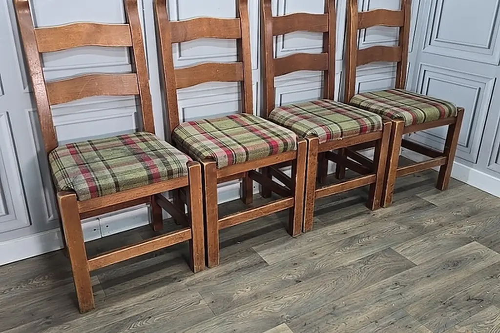 Wooden dining chairs with green and red plaid seat cushions.