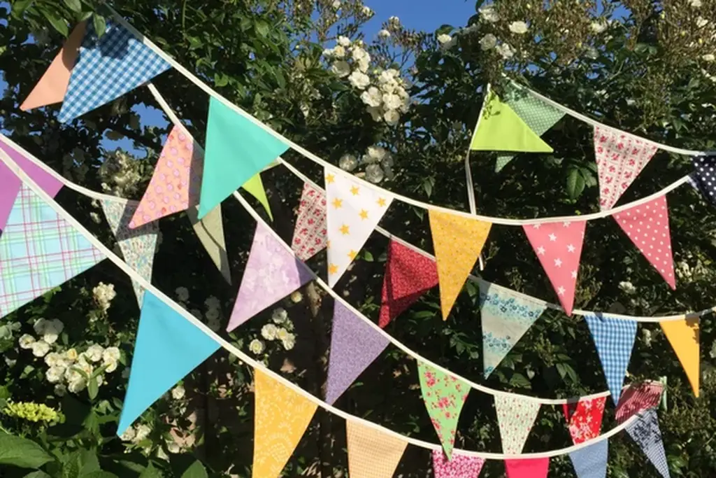 Colorful fabric bunting strung across a garden seating area.