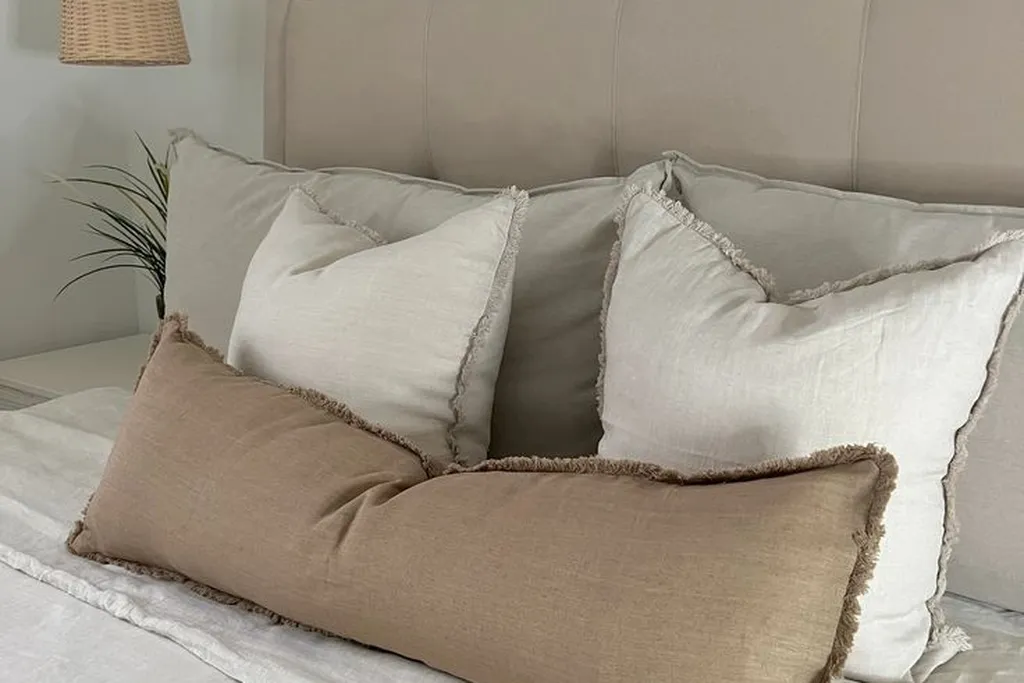 Knit and linen cushions arranged on a bed in neutral tones