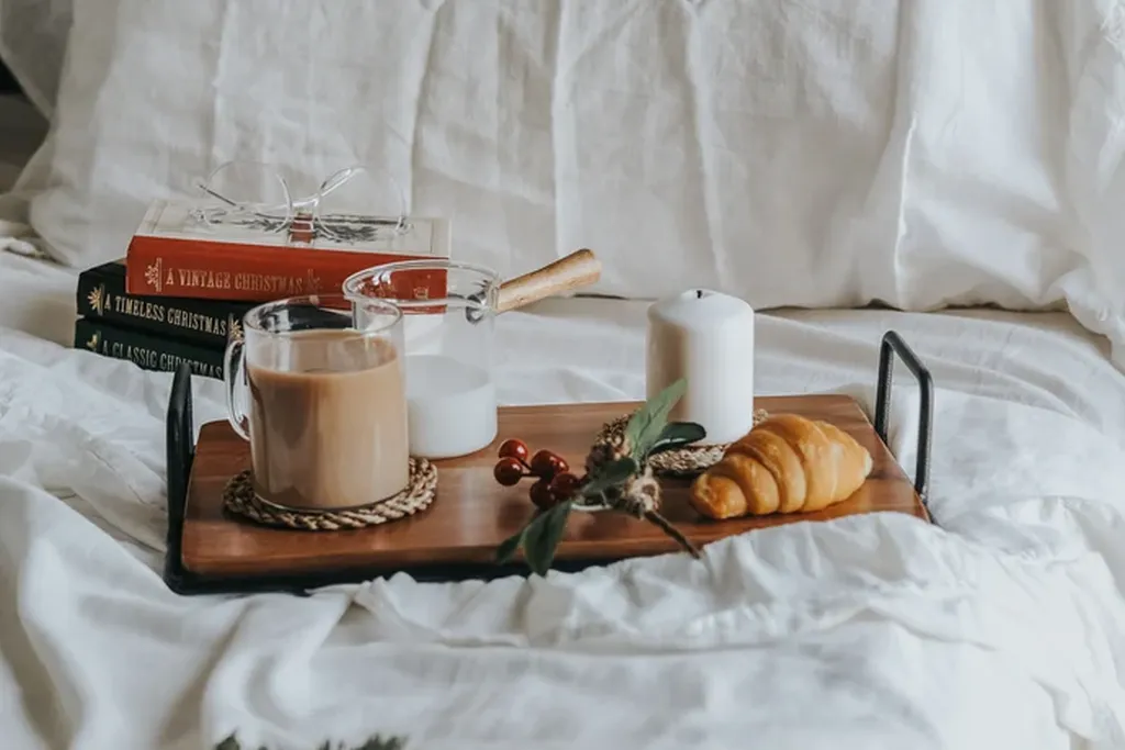 Tray with a mug and book on a bed in morning light