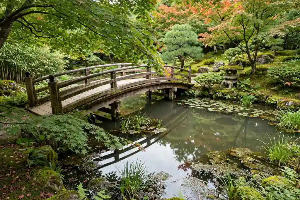 Small arched wooden bridge over a still pond with maples nearby.