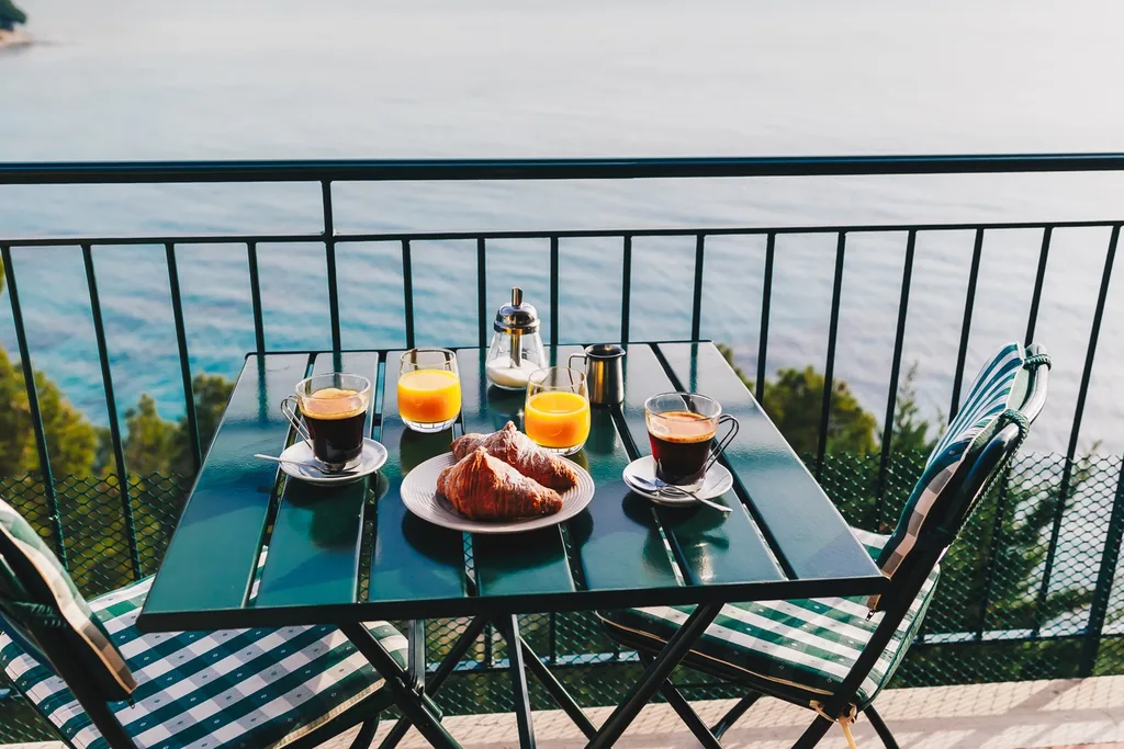 Balcony table set for breakfast for two in morning light.
