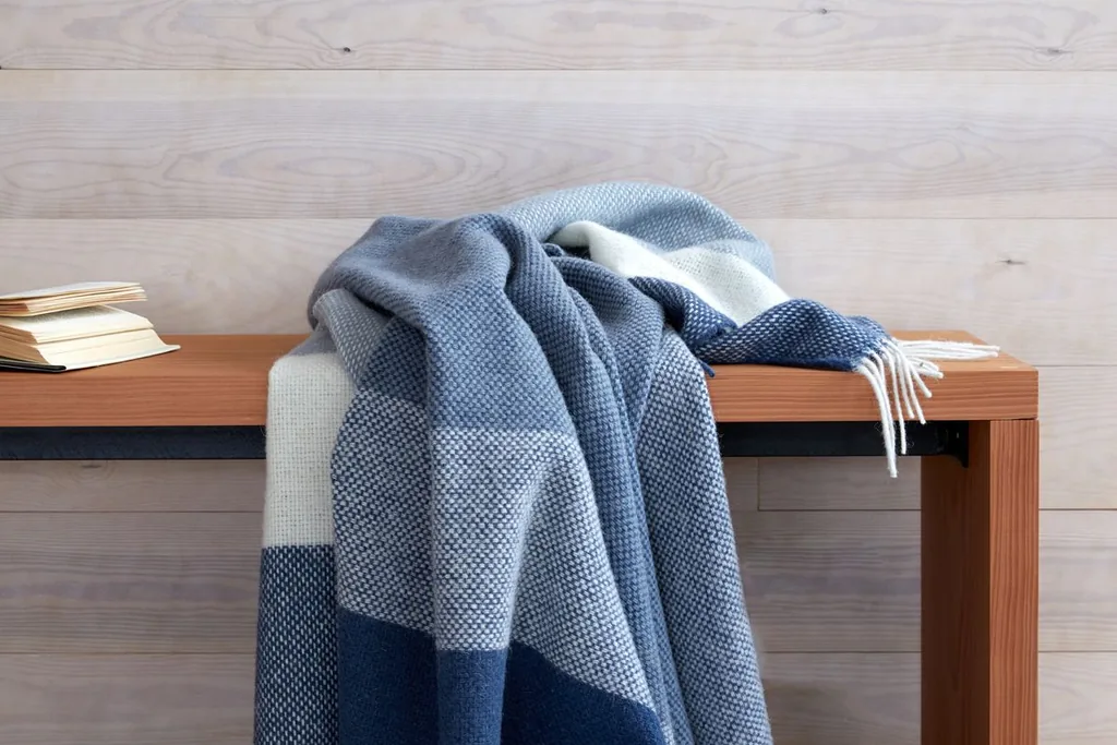 Folded throw draped over the back of a bench.