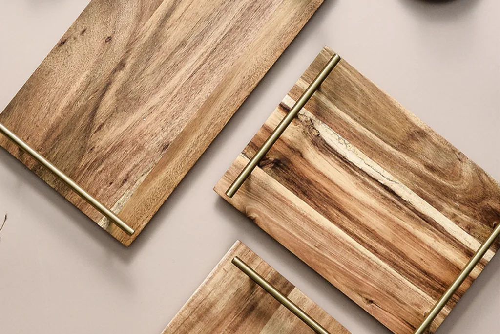 Wooden serving trays with brass handles on a table.
