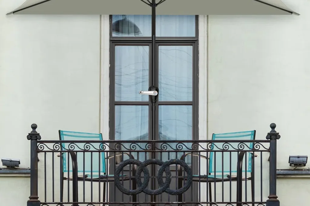 Shade umbrella over a small balcony with chairs behind the railing.