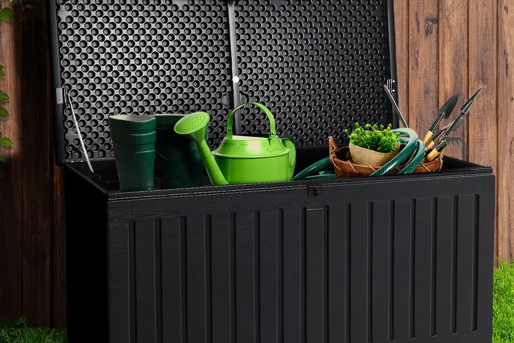 Weatherproof storage box open with garden tools and a watering can inside.
