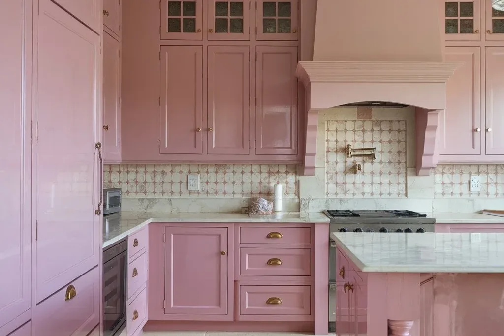 Kitchen with blush pink cabinets and white counters.