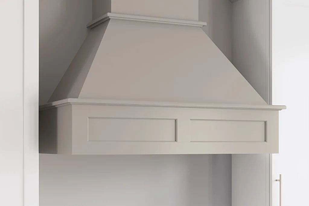 Flat panel cabinet style range hood in a pale painted finish fitted between cabinets.