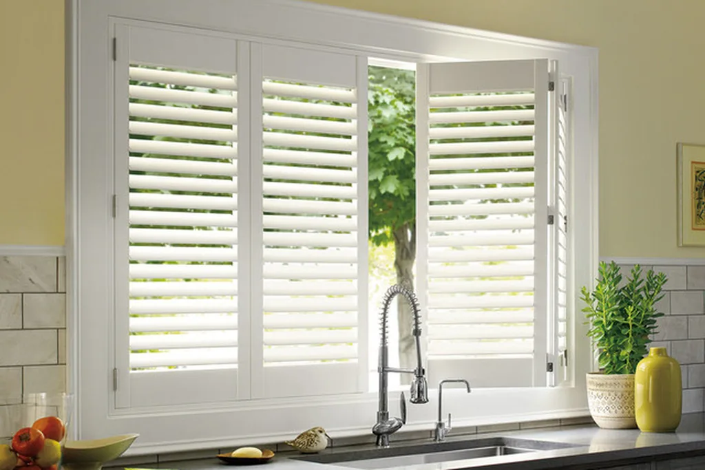 White interior shutters fitted to a kitchen window above the sink.