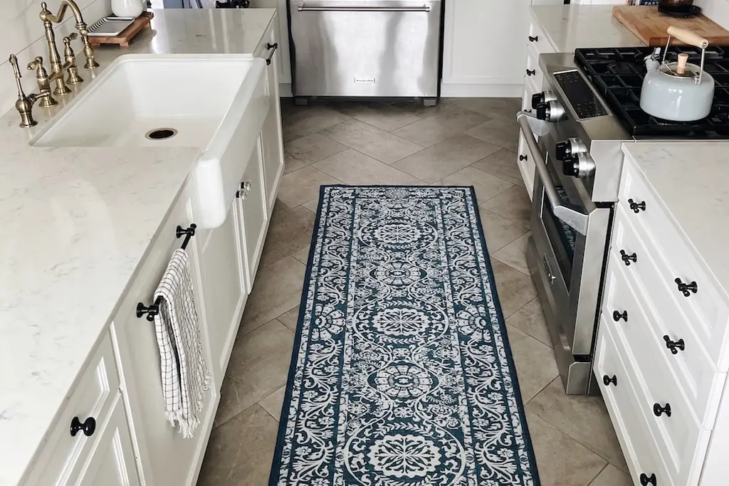Long patterned blue runner rug on the floor of a galley kitchen in front of white cabinets.