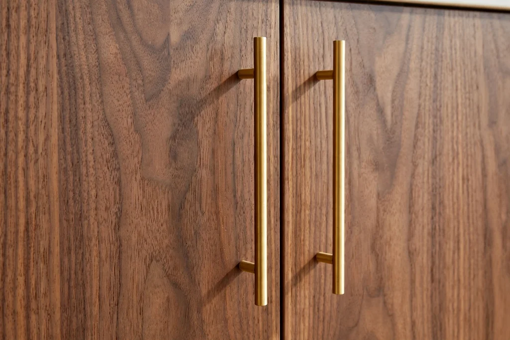Slim brass bar pulls on flat-front walnut kitchen cabinet doors.