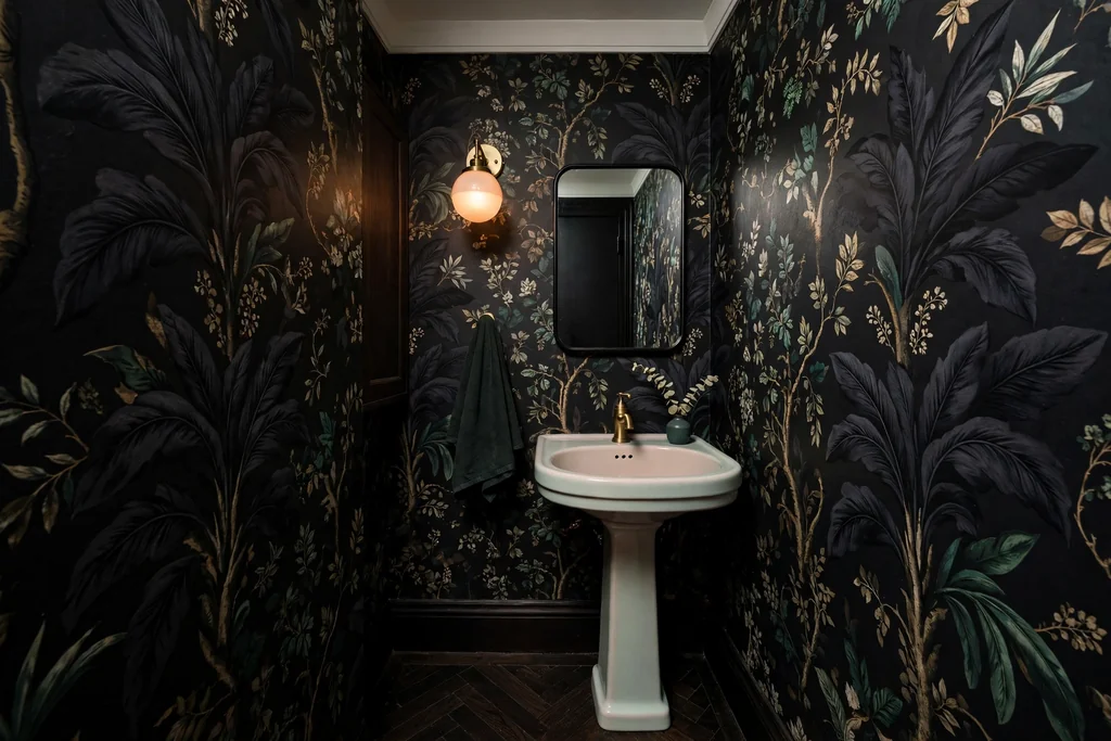 Small dark powder room with bold dark wallpaper and a pale basin.