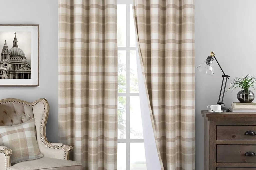 Windowpane plaid curtains in cream and gray hanging floor length beside a window