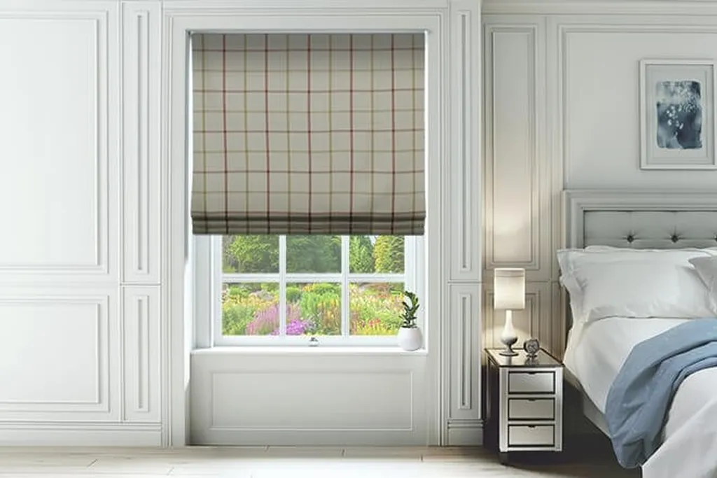 Plaid Roman shade at a small bedroom window next to a bed with solid bedding