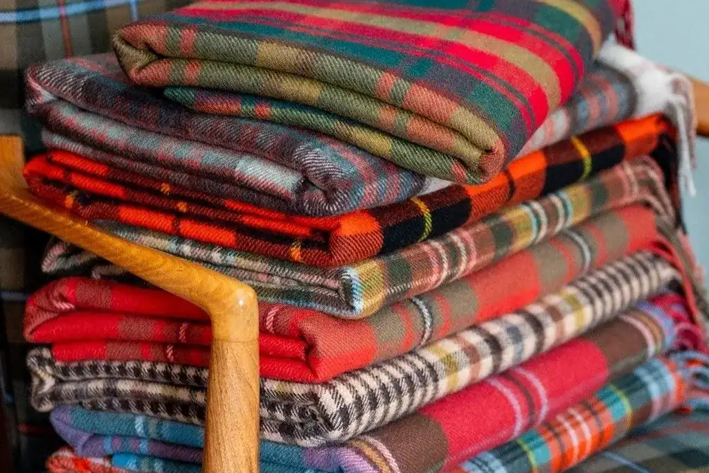 Wool plaid blanket hanging as a wall panel above a bed headboard