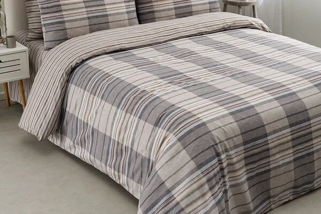 Plaid duvet paired with a thin striped sheet and solid cushions on a bed