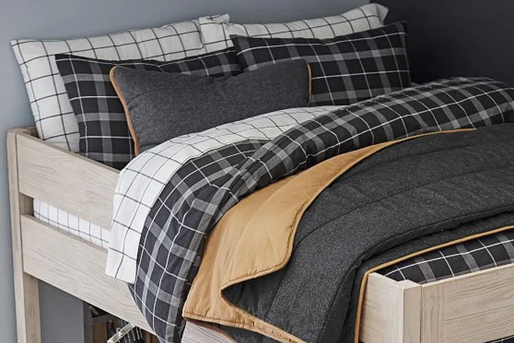 Teen bedroom with black and white plaid bedding and a single accent cushion