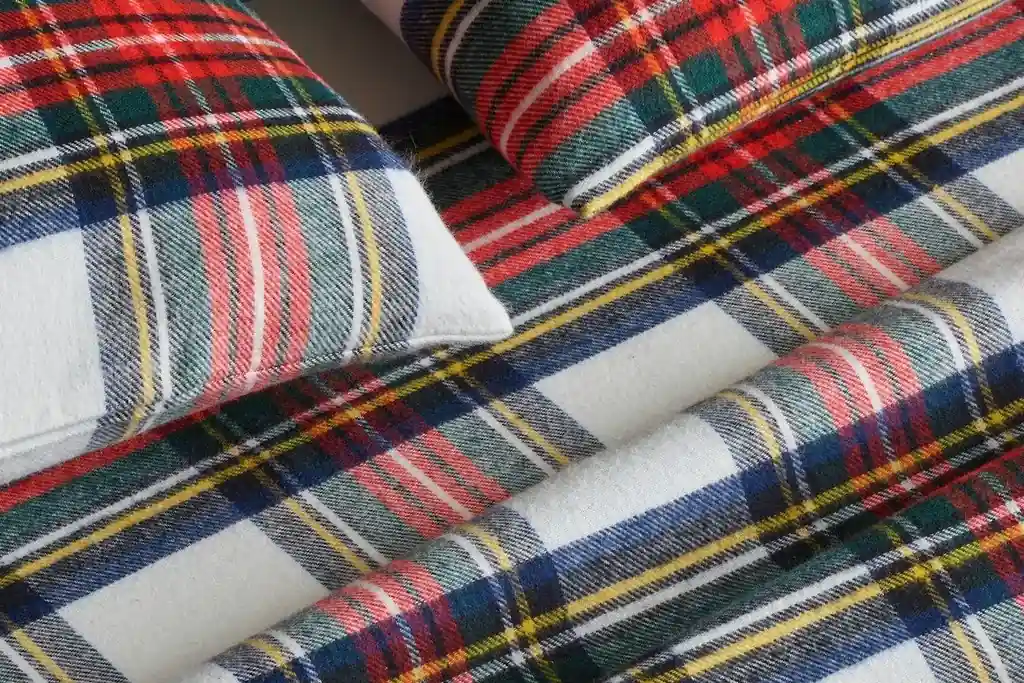 Plaid flannel sheet showing as a folded band over a solid duvet on a bed