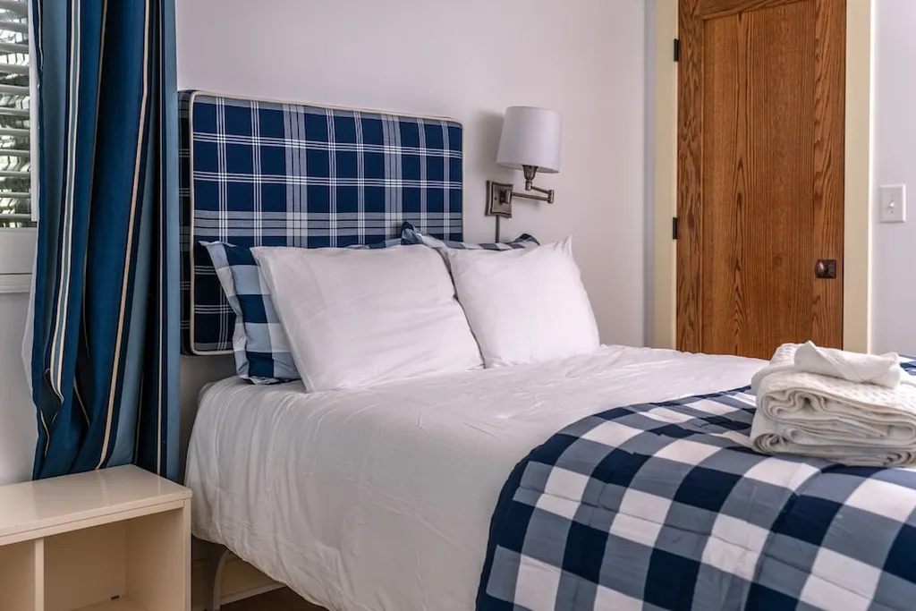 Guest bedroom bed with a folded plaid throw and plaid pillow shams