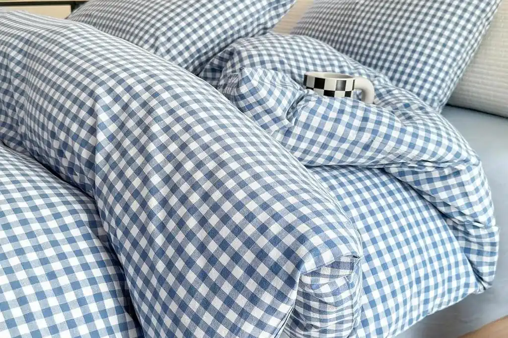 Small gingham check bedding in pale blue on a bed in a bright small bedroom