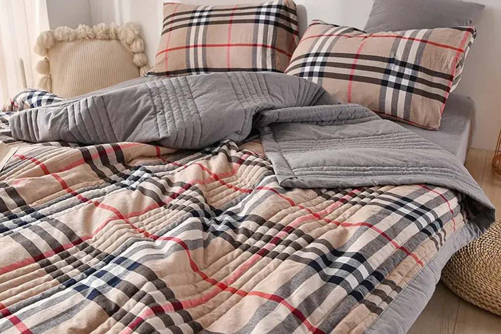 Plaid quilt folded over the lower half of a plain duvet on a bed