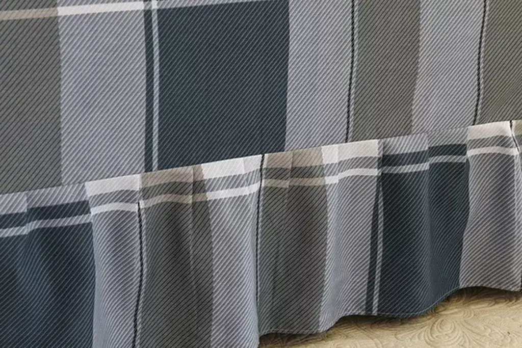 Plaid bed skirt in a small check covering the base of a bed with plain bedding