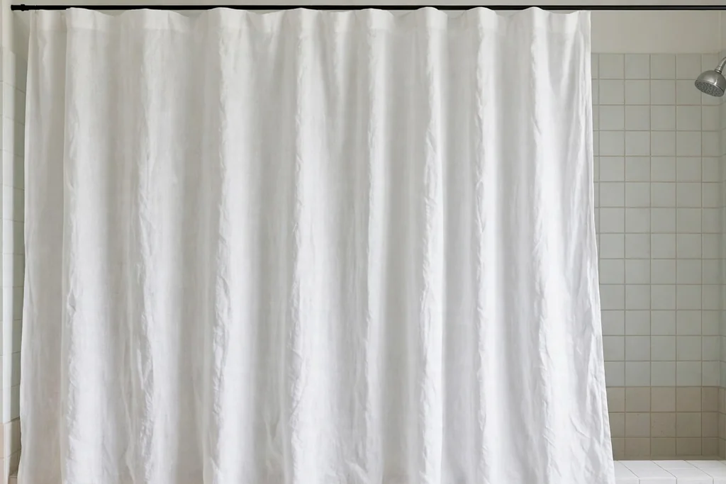 Natural linen look shower curtain in soft white hanging in a bright bathroom.