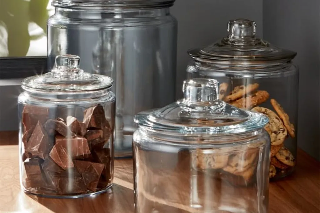 Glass canisters with lids holding baking staples on a wood counter.